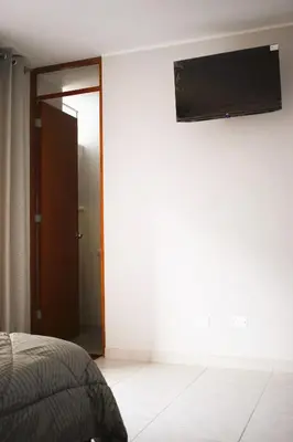 a bedroom with a bed and a flat screen tv on the wall at El Valle - Lunahuaná in Lunahuaná