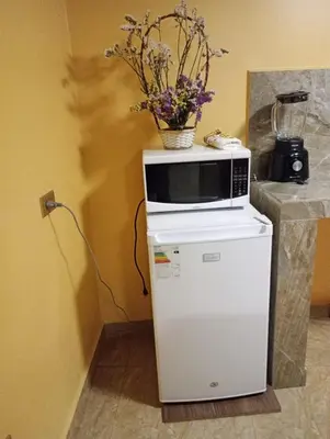a microwave sitting on top of a refrigerator at Gia's apartments in Cusco