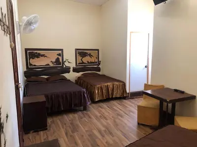 a room with two beds and a table in it at Hostal Huacachina Sunset in Ica