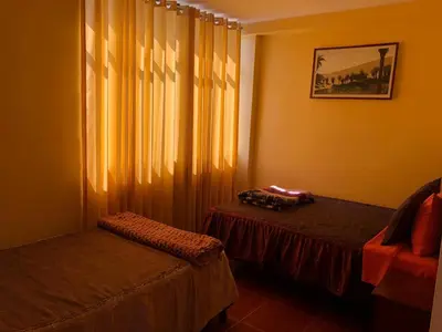 a bedroom with two beds and a window with curtains at Hostal Huacachina Sunset in Ica