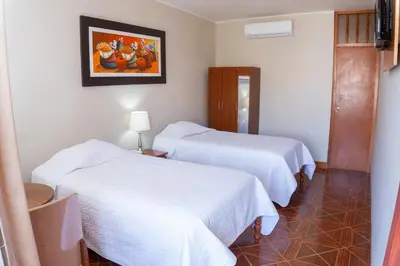 a hotel room with two beds and a painting on the wall at Hotel Curasi in Ica