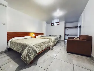 a hotel room with two beds and a couch at Excelente ubicación! Bellas y cómodas habitaciones en el centro de Oxapampa in Oxapampa