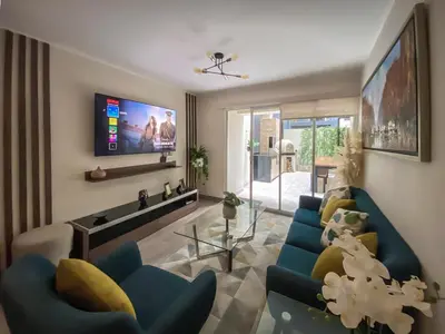 a living room with two blue chairs and a flat screen tv at Silvia's New Spacious Patio Pad in Lima