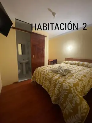 a bedroom with a bed with a bathroom sign on the wall at CASA ALVAREZ in Cusco