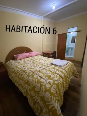 a bedroom with a bed with aption sign on the wall at CASA ALVAREZ in Cusco