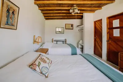 two beds in a room with a wooden ceiling at Hotel Fundo El Arrabal in Ica