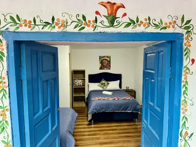 a bedroom with a bed with a blue door at AITANA'S HOUSE - SAN BLAs in Cusco