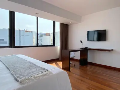 a bedroom with a bed and a desk with a flat screen tv at Modern Penthouse & 2BR in Miraflores by Wynwood House in Lima