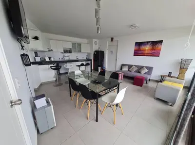 a kitchen and a living room with a table and chairs at Departamento de Playa (con piscina propia) en km 107 Asia, Lima in Asia