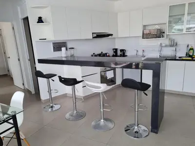 a kitchen with a counter with four bar stools at Departamento de Playa (con piscina propia) en km 107 Asia, Lima in Asia