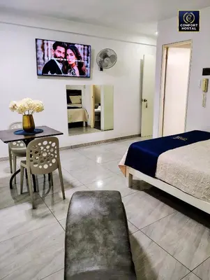 a bedroom with a bed and a table and a tv at Hospedaje Comfort Lima in Lima
