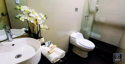 a bathroom with a sink and a toilet and flowers at Hospedaje Comfort Lima in Lima