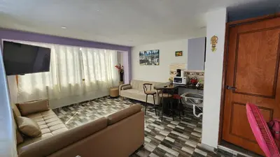 a living room with a couch and a table and a kitchen at TRANSFER VIP HOSTEL in Lima