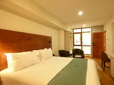 a hotel room with a bed and a table and chairs at Muña Hotel Andahuaylas in Andahuaylas