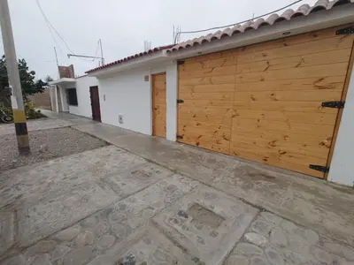 a building with a wooden garage door and a sidewalk at Hostel Killamoon Centro in Paracas