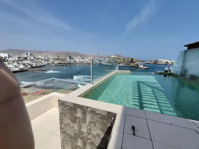 a swimming pool on top of a building with a view of the water at Excelente departamento frente al mar. in San Bartolo