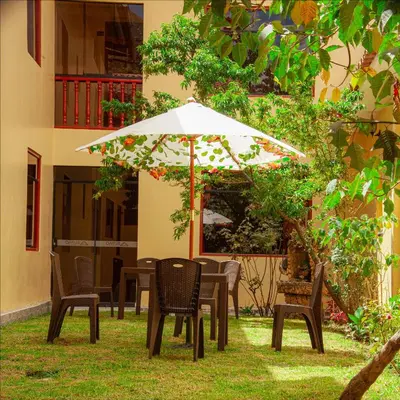 a table and chairs under an umbrella in the grass at Hotel Valle Mistico in Ollantaytambo