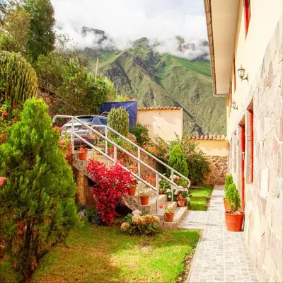 a house with a garden and mountains in the background at Hotel Valle Mistico in Ollantaytambo
