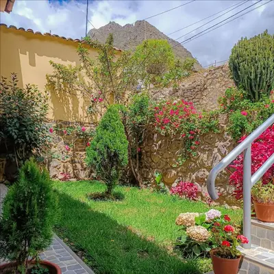 a garden with flowers and a stone wall at Hotel Valle Mistico in Ollantaytambo