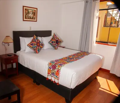 a bedroom with a white bed with colorful pillows at Hotel Valle Mistico in Ollantaytambo