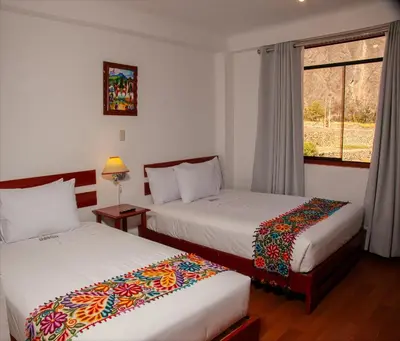 two beds in a room with a window at Hotel Valle Mistico in Ollantaytambo
