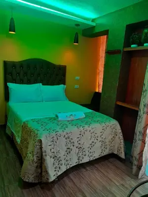 a bedroom with a bed with a green wall at HOTEL LA BELLA Y EL LEON in Huánuco