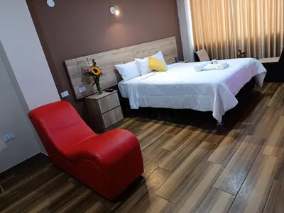 a hotel room with a bed and a red chair at Arabian Hotel in Lima