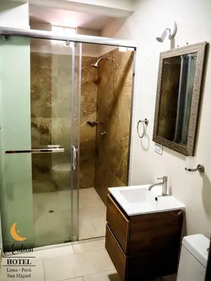 a bathroom with a glass shower and a sink at Arabian Hotel in Lima