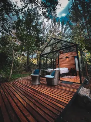 a wooden deck with two chairs and a bed in a gazebo at Oasis Blue Oxapampa in Palmira