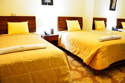 two beds in a hotel room with yellow sheets at Hotel Sol del Sur in Nazca