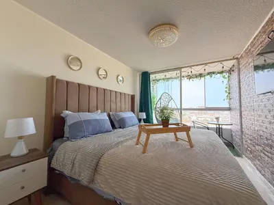 a bedroom with a bed with a wooden headboard and a table at Departamento con vista al mar y piscina - Pool One in Lima