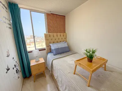 a small bedroom with a bed and a table at Departamento con vista al mar y piscina - Pool One in Lima