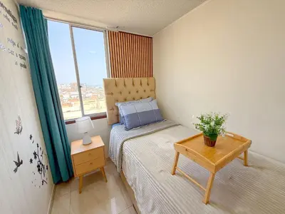 a small bedroom with a bed and a table at Departamento con vista al mar y piscina - Pool One in Lima
