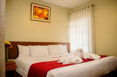 a bedroom with a bed with a red blanket and a window at HOSTAL CASA INKAS in Cusco