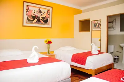 two beds in a room with yellow walls at HOSTAL CASA INKAS in Cusco