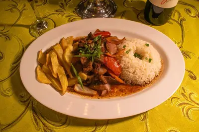 a plate of food with rice and meat and french fries at Hacienda Santa María de Cieneguilla in Cieneguilla