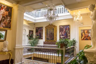 a hallway with paintings on the walls and a chandelier at Casa Lima in Lima