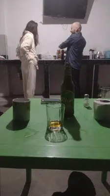 a man and a woman standing in a kitchen with a green table at Nomads Club in Nazca