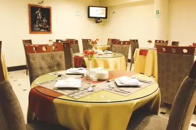 a dining room with tables and chairs and a television at Hotel B&V in Huancayo