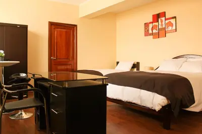 a hotel room with two beds and a desk at Hotel B&V in Huancayo