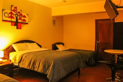a bedroom with two beds and a table with a lamp at Hotel B&V in Huancayo