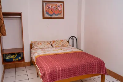 a small bedroom with a bed with a red blanket at Yaki Hostel in Lima
