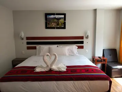 two swans are sitting on top of a bed at Raymi MachuPicchu in Machu Picchu