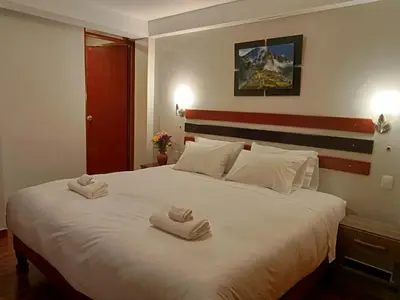 a bedroom with a large white bed with towels on it at Raymi MachuPicchu in Machu Picchu