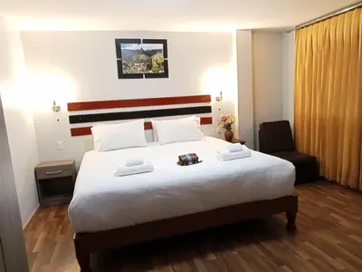 a hotel room with a large bed and a chair at Raymi MachuPicchu in Machu Picchu