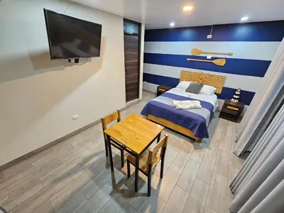 a bedroom with a bed and a table and a tv at EL FARO HOTEL in Chala