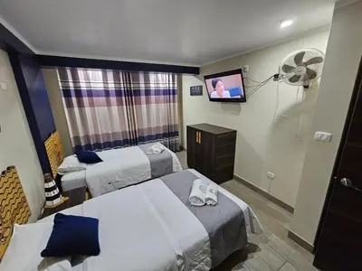 a hotel room with two beds and a flat screen tv at EL FARO HOTEL in Chala