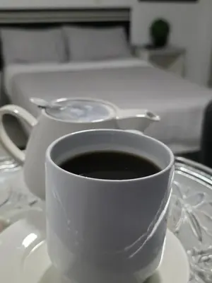 a cup of coffee sitting on a plate next to a bed at Hotel Real San Pedro in El Puente