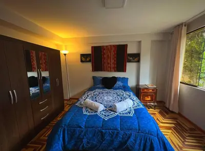 a bedroom with a blue bed and a window at Kintu Apartamento cusco in Cusco