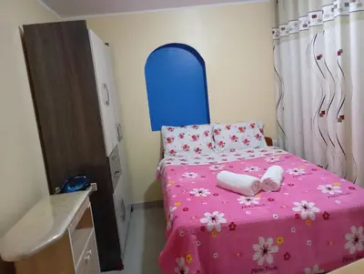 a small bedroom with a pink bed with a blue headboard at Mi hermosa Casita con baño y cocina privados in Lima